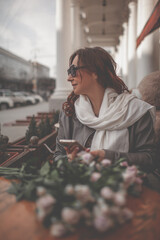 A charmig middle-aged woman wate the order a french cafe on a city street. A woman with flowers is...