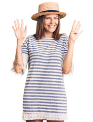 Obraz na płótnie Canvas Beautiful caucasian woman wearing summer hat showing and pointing up with fingers number nine while smiling confident and happy.
