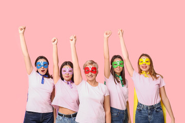 Women in superhero costumes on pink background. Women's history month