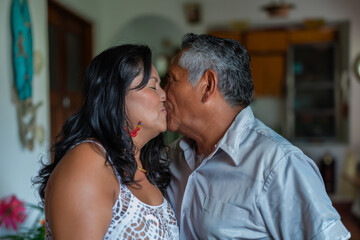 A man and woman are kissing in a living room