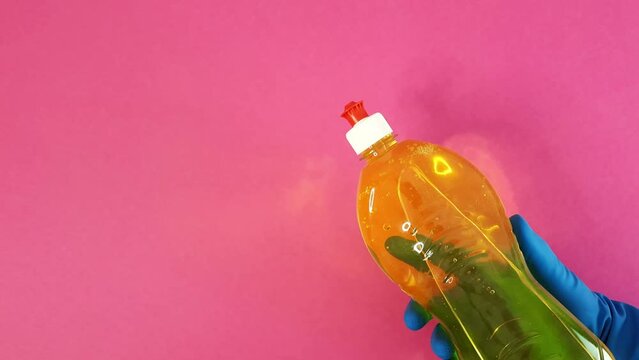 Person holding a bottle of detergent in his hand. Detergent liquid in hand in blue glove. Cleaning Services Concept - house, apartment, office cleaning. Template with place for text, advertising, logo