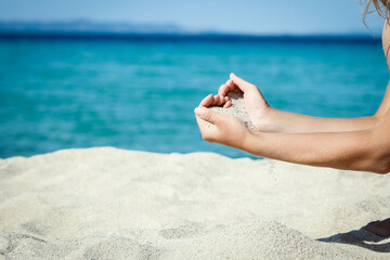 Fototapeta na wymiar A hands pouring sand near the seashore on weekend nature travel