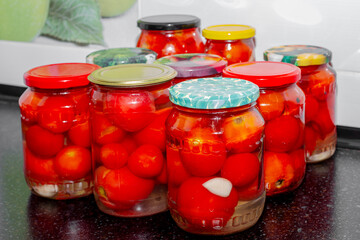 Glass jars with red tomatoes filled with brine. Preparations for the winter, canning tomatoes