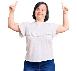 Brunette woman with down syndrome wearing casual white tshirt smiling amazed and surprised and...