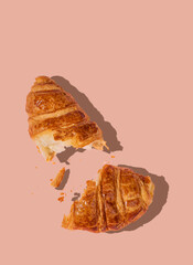 Flat lay of  fresh broken croissant on beige background with shadow. Creative layout and concept of healthy food and french breakfast.