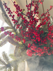a bouquet of branches with red berries and fir branches in smoke in sunny weather, the rays of the sun through the branches