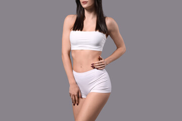 Obraz premium Beautiful young woman in white underwear on grey background