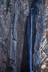 Small waterfall in rock, close up. Stream of water, mountain stream flowing. spring melting of glaciers in mountainous areas. 