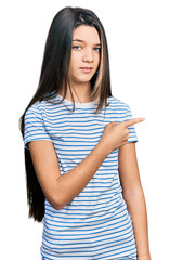 Young brunette girl with long hair pointing with fingers to the side clueless and confused...