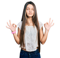 Young brunette girl with long hair wearing white shirt relaxed and smiling with eyes closed doing meditation gesture with fingers. yoga concept.