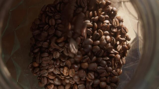 Close-up of coffee beans cascading into a glass jar
