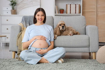 Beautiful pregnant woman with cocker spaniel on sofa at home