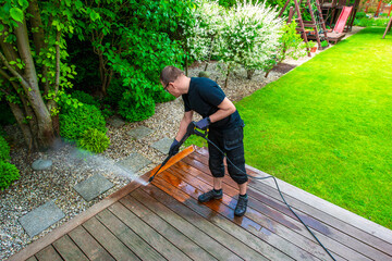 man cleaning terrace with a power washer - high water pressure cleaner on wooden terrace surface - 775305093