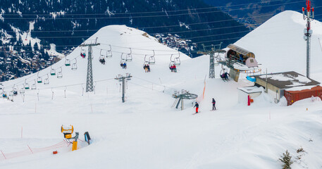 Aerial shot of Verbier, Switzerland shows snow slopes, ski lifts, and cable cars on the mountain....