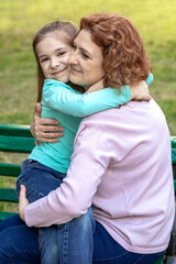 Mother and daughter hugging in the park in summer.