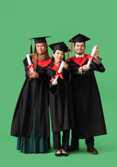 Graduate students holding diplomas on green background