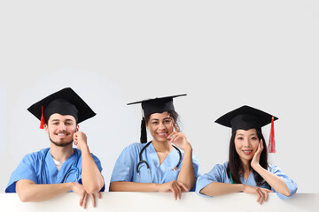 Medical graduate students with blank poster on white background