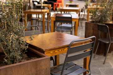 Outdoor street cafe tables ready for service. Empty cafe terrace with wooden table and plastic chair, morning time. Food concept