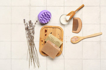 Hair scalp massager with shampoo bars, brush and sea salt on white tile background