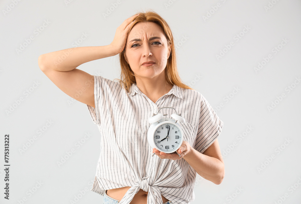 Sticker Mature woman with alarm clock on light background. Menopause concept