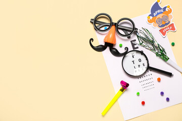 Eye test chart, magnifier and party decor for April Fools Day celebration on color background