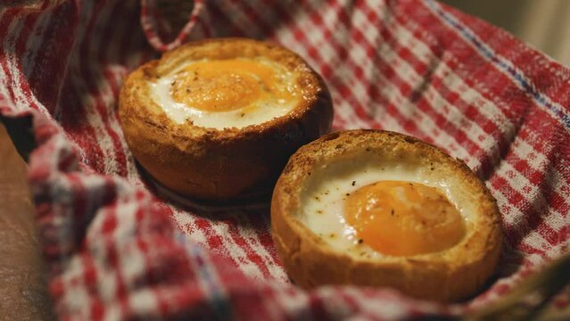 Oven baked eggs in buns. Fried eggs in bread on a rustic towel.