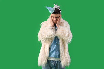 Young man with hangover after Birthday party on green background