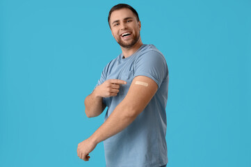 Young man with applied medical patch on blue background. Vaccination concept