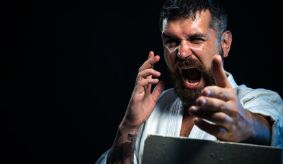 Bearded determined karate man breaking with hand concrete brick. Screaming karate fighter showing kick by hand. Angry karate master in kimono preparing for competition. Copy space for advertising. - obrazy, fototapety, plakaty