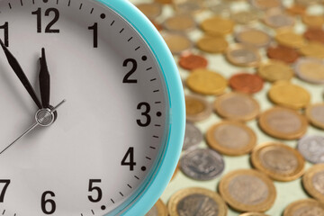 Composition with blue alarm clock and lots of coins on green background. Time management concept. Closeup