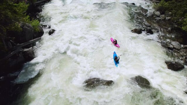 Two Whitewater Kayakers Followed by Drone on River Rapids