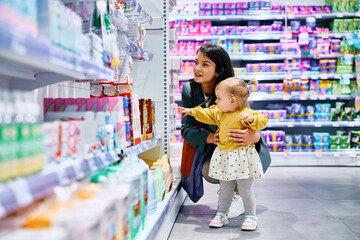 Small girl and her mother shopping at store.