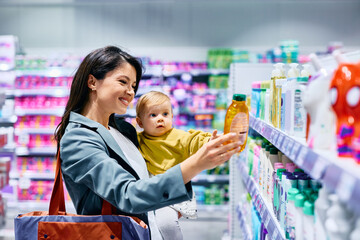 Happy woman buying shampoo for her small daughter at drugstore.