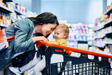 Happy mother and daughter having fun while shopping in supermarket.