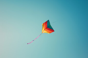 Colorful raindbow kite flying in blue sky with fluffy clouds