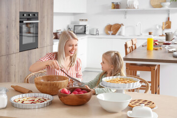 Happy mother with her little daughter cooking apple pie in kitchen
