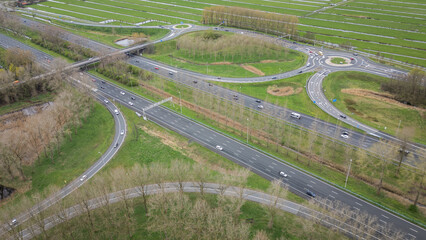 Dutch roundabout on road N459 from A12 at Reeuwijk near Gouda in Netherlands. Traffic flows at efficient pace with cars in highway lanes entering and exiting motorway. drone aerial view of transport
