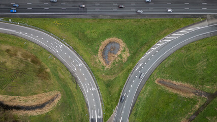
entrance and exit on Dutch Highway road A12 at Reeuwijk near Gouda in Netherlands. Traffic flows at efficient pace with cars in lanes entering and exiting motorway. drone aerial view of transport
