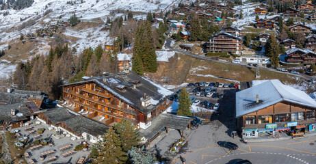 Aerial panoramic view of the Verbier ski resort town in Switzerland. Classic wooden chalet houses standing in front of the mountains.  - Powered by Adobe