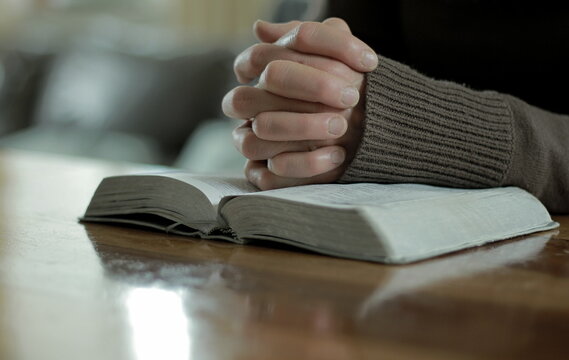 praying to God with the bible on black background with people stock image stock photo