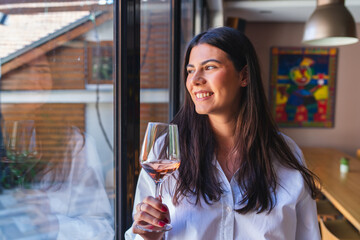 One young woman or girl is holding glass of wine and drinking wine in winery while enjoying and smiling