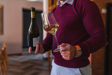 A close up of man's hands opening and pouring white wine in wine glass