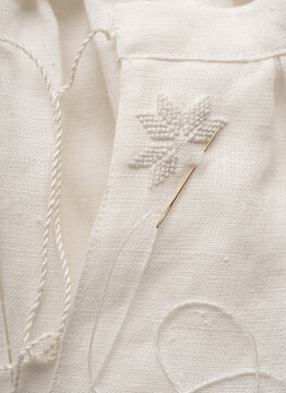 close-up of natural linen fabric with an element of traditional Ukrainian embroidery - a star. embroidery with white threads on white fabric, the process of creating a vyshyvanka