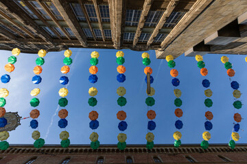 Bunte Schirme zwischen zwei Hausw&auml;nden h&auml;ngen &uuml;ber einer Stra&szlig;e