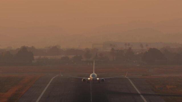 Airplane accelerating on runway with lift-off against a hazy evening backdrop