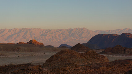 The Timna Valley, cast in the warm light of dawn, stands still as ancient mountains watch over this...