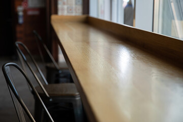 The wooden bar table near the window is empty.
