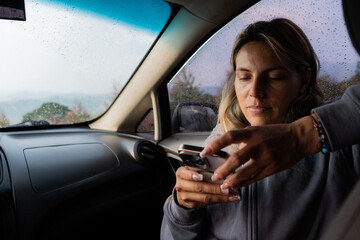joven mujer en el interior de su carro escribiendo un mensaje de texto en el celular 