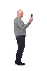 side view of a smiling man taking a self-portrait with smartphone on white background - 775352099