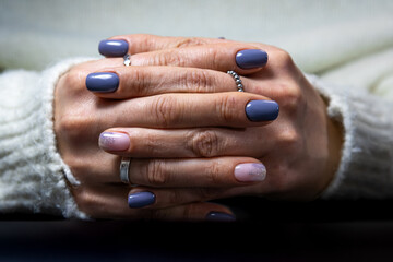 Crossed hands with blue manicure and sparkling rings